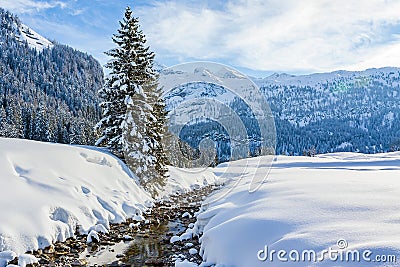 Through this unique mountain landscape of â€‹â€‹Gnadealm Obertauern, Austria, this small river meanders past beautiful sno Stock Photo